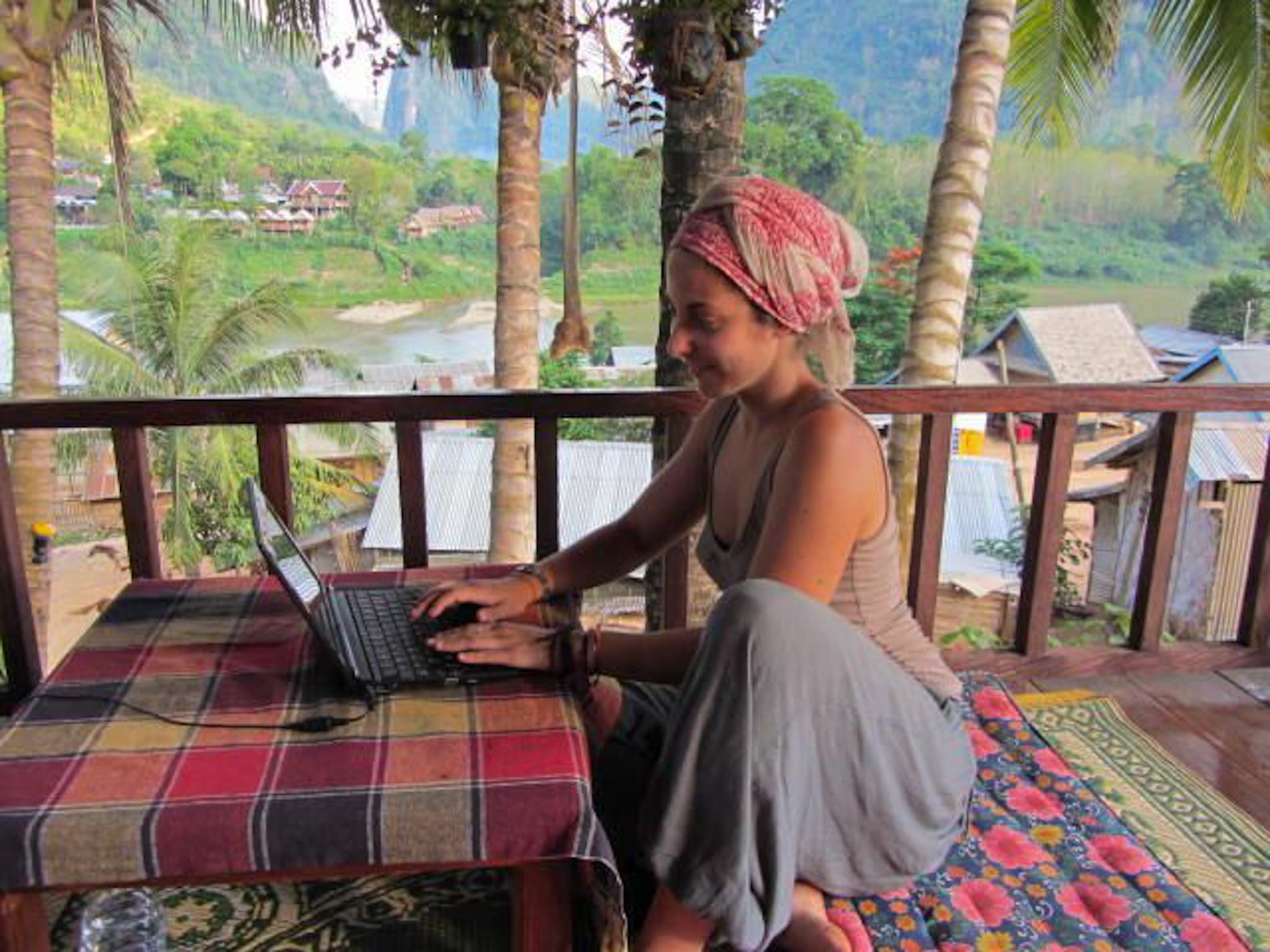 Maite trabajando desde una terraza con vistas al río en Laos