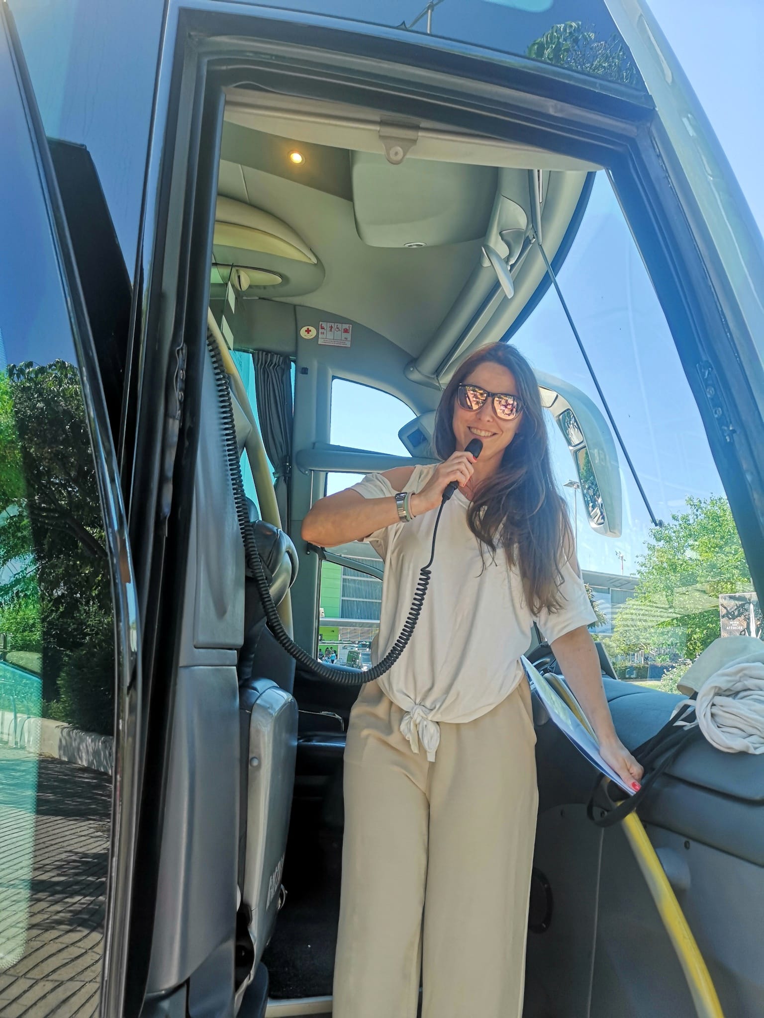 Maite guiando con micrófono a la entrada de un autobús